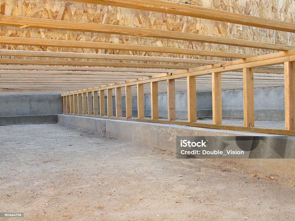 Wooden floor joists and beams in a crawl space beneath a building.