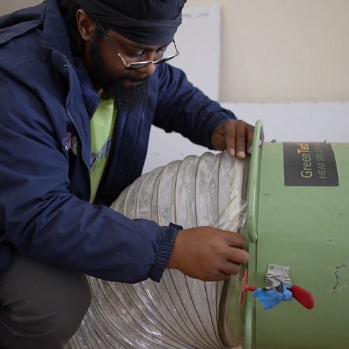 Man inspecting a flexible duct connected to a green unit.