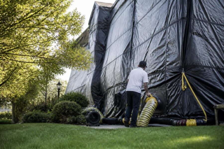Pest control worker attaching hose to tented house